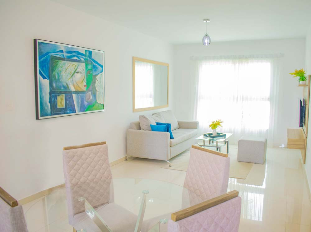 Glass dining table with chairs in the dining room and a view of the living room at Beach Apartamentos in Playa Palmera